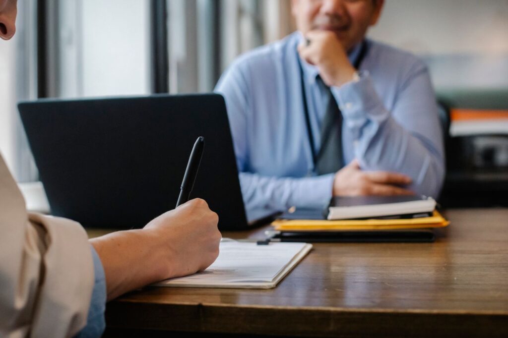 a close-up of a job interview interaction with documents and a laptop in an office