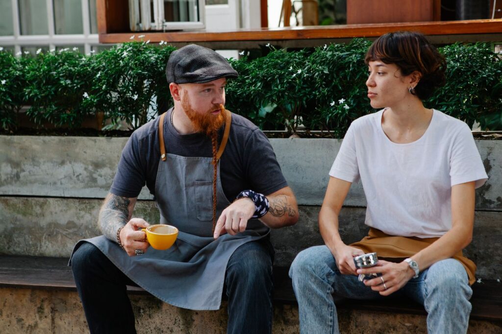two café employees sitting outside engaging in small talk