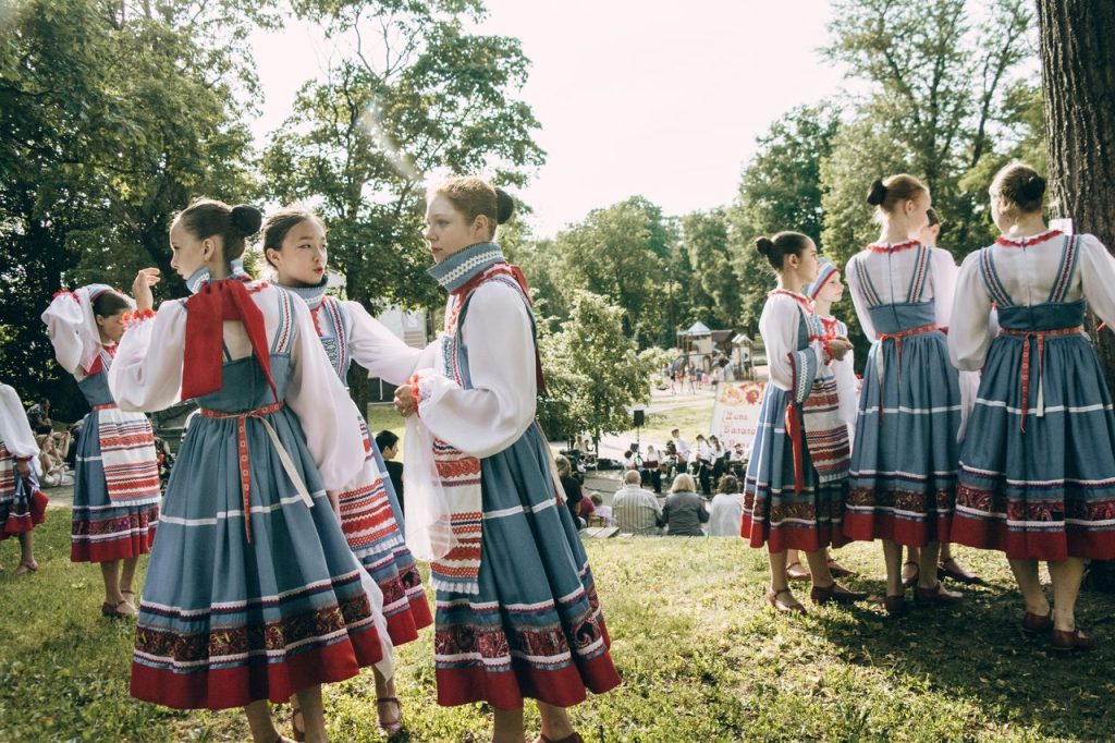 A group of young women in traditional folk dance costumes at an outdoor festival
